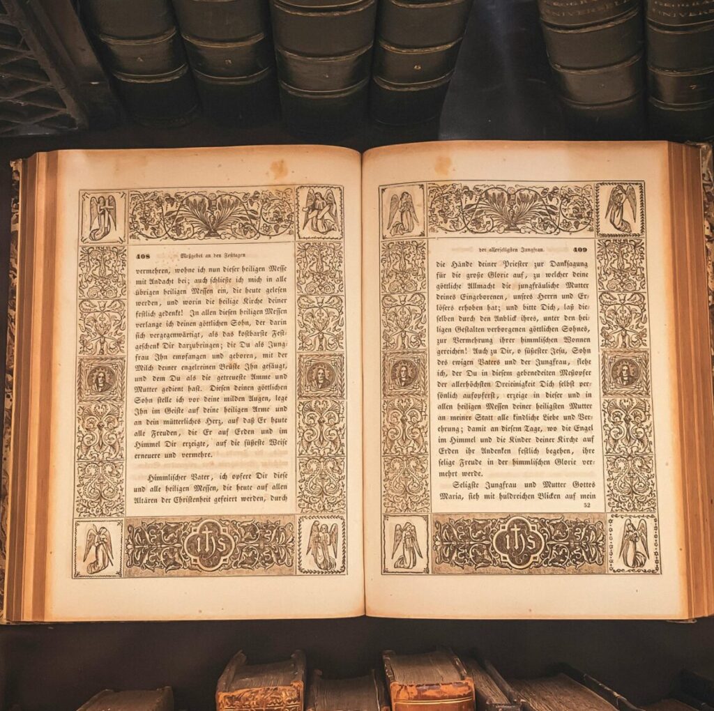 A vintage book displayed in an antique library setting with an open ornate book highlighted.